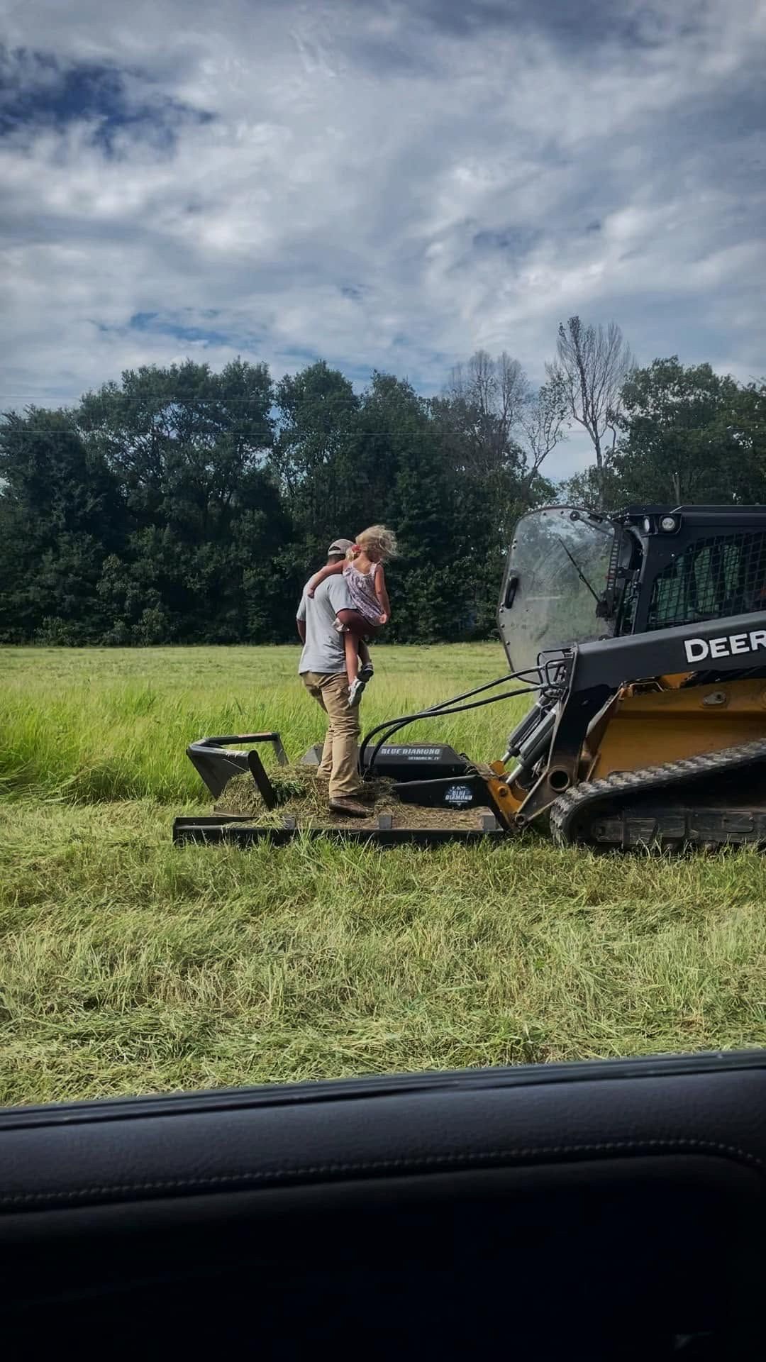 Tyler with his family in the pasture, working the mower attachment