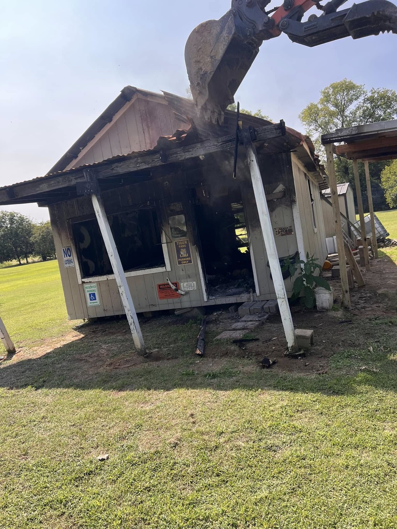 Excavator tearing into a fire-damaged structure